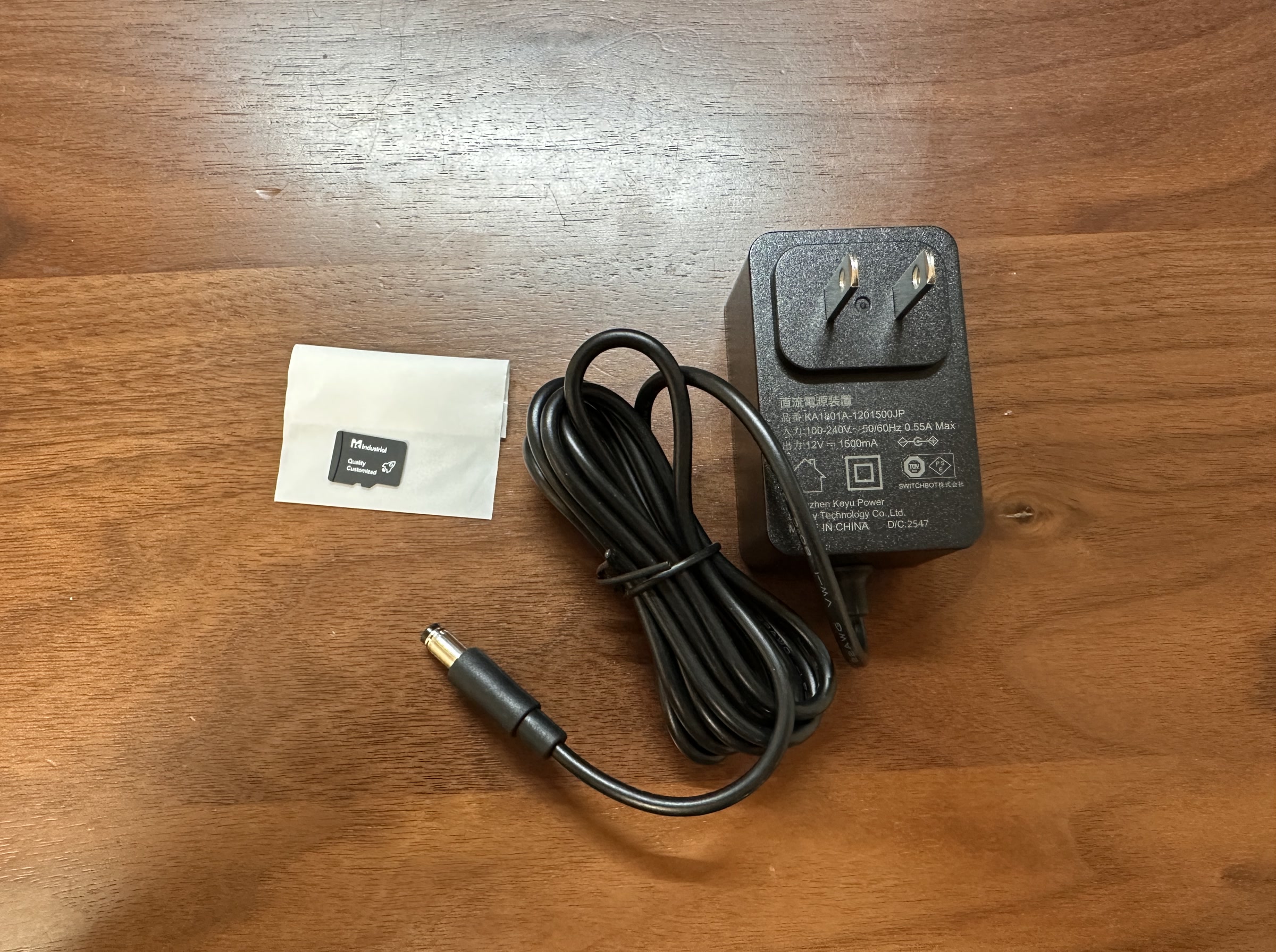 SwitchBot AIハブの同梱物。電源アダプター、ケーブル、microSDカードが並んでいる